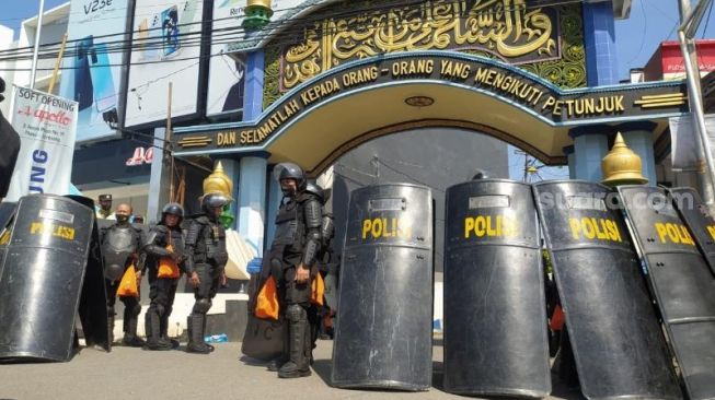 
					Personel kepolisian dari Polda Jatim berjaga di gerbang Pesantren Shidiqqiyah, Ploso, Jombang, Kamis (7/7/2022). [SuaraJatim.id/Zen Arivin]